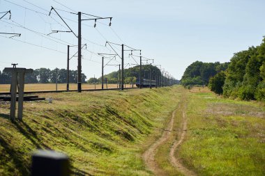 Gün batımında arka planda yeşil ve mavi gökyüzü olan demiryolu manzarası