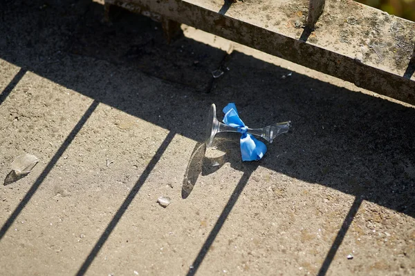 Mavi kurdeleyle bağlanmış kırık bir düğün bardağının yakın çekimi.