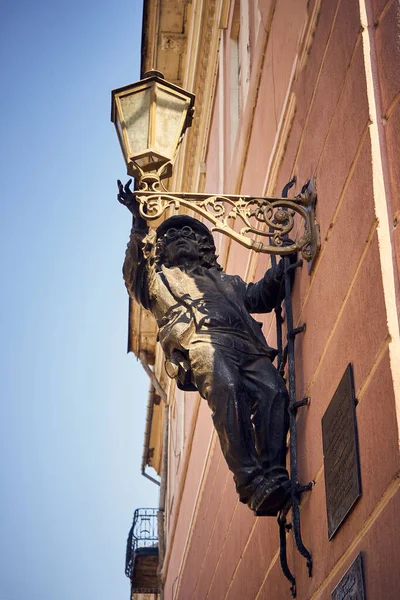 Dışarıdaki ampulü vidalayan bir adamın demir heykelinin dikey çekimi.