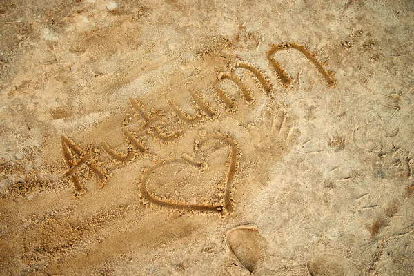 Günbatımında kumun üzerinde bir kalple 