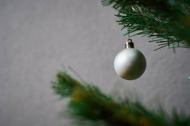 Gri Yeni Yıl oyuncağı Noel ağacında asılı gri bir duvara