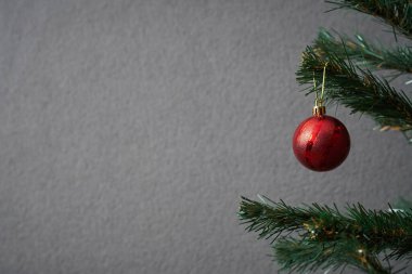 Gri arka planda Noel ağacı ve büyük kırmızı top