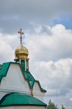Ortodoks kilisesinin tepesinin dikey fotoğrafı bulutlu mavi gökyüzüne karşı.
