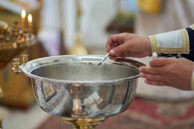 Bir çocuğun vaftiz töreni sırasında kilise rahibi tarafından kutsanmış suyun fotoğrafı.