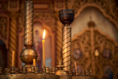 Kilisenin kaidesinde yanan bir mumun yakın çekimi.