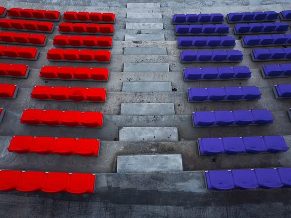 Seats of a football stadium in different colors. Red VS blue.