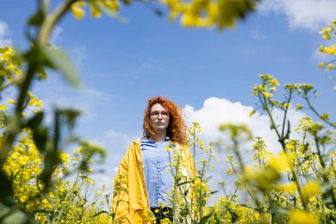 Young determined woman standing in a yellow field