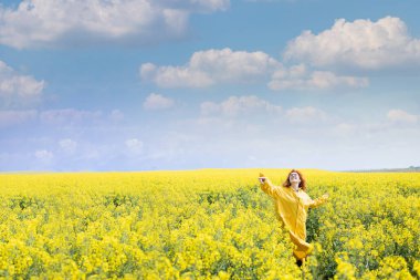 A woman dancing in the field on spring day and expressing positivity