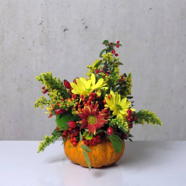 floral arrangements in orange mini pumpkin, floral decor from lot of various flowers and plants in pumpkin