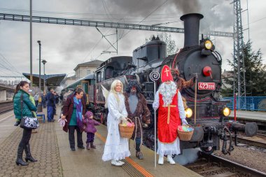 Kasım 2013 'te Chocen' den Litomysl 'e tren yolculuğu. Aziz Niklas, melek ve şeytanlar buharlı bir lokomotifin yanında.