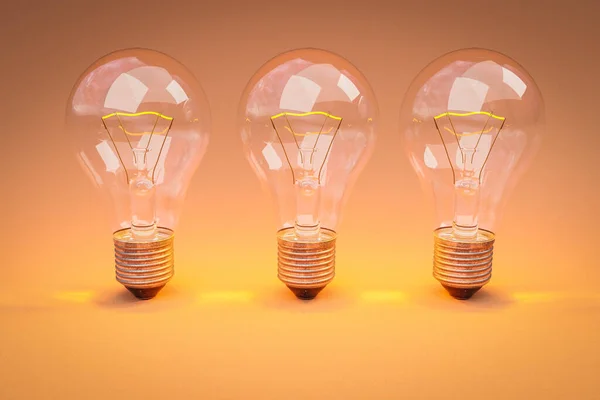 stock image three retro style lightbulbs with glowing filament standing in row on infinite colorful orange background; creativity design concept; 3D Illustration