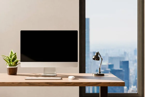 frontal view on modern clean pc workplace; black monitor with copy space; minimalist office background with panoramic view on big city skyline; home office concept; 3D rendering