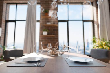 Zeminden tavana pencereli ve panoramik manzaralı lüks çatı katında yemek masasının yakın plan görüntüsü; modern minimalist iç tasarım; parlak gün ışığı; 3D görüntüleme