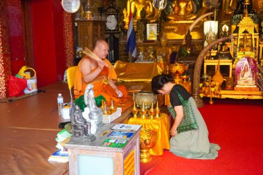 Wat Prai Doi Suthep, Tayland 'daki altın tapınağında bir keşişin önünde diz çöken bir kadın.
