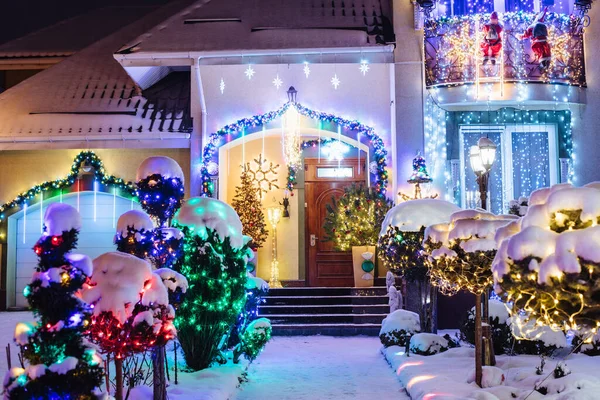 这所房子装饰着圣诞彩灯和装饰品 包括夜里点亮的圣诞老人和圣诞树 图库照片