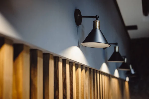 Black lamps indicate a gray wall decorated with wooden lines, background for interior design. Interior decoration of stylish housing. Retro loft style lamp. Home design in a modern style.  film noise