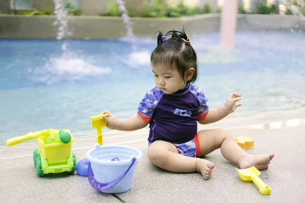プールで水遊びをしているアジア系の女の子 トロピカルビーチ島の夏休みに屋外スイミングプールで遊んでいる女の子 子供は高級リゾートの屋外プールで泳ぐことを学ぶ 子供のための水おもちゃ ストック写真