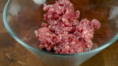 Chef hands in transparent gloves mix minced meat with spices in glass bowl. Preparation tasty food on domestic kitchen. Clos-up.