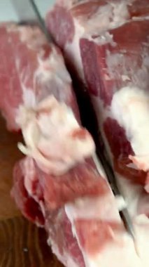 Chef cut quality raw meat with sharp knife into steak before cooking. Preparation tasty food on domestic kitchen. Vertical. Close up.