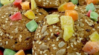 Fresh homemade oatmeal cookies sprinkled with sesame and candied fruit rotate. Simple homemade healthy bakery. Food background. Close up.