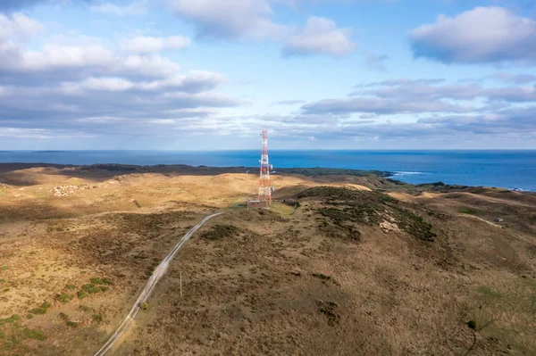 Drone aerial photograph of a large communications tower in a large agricultural field near the coast in Currie on King Island in Tasmania in Australia