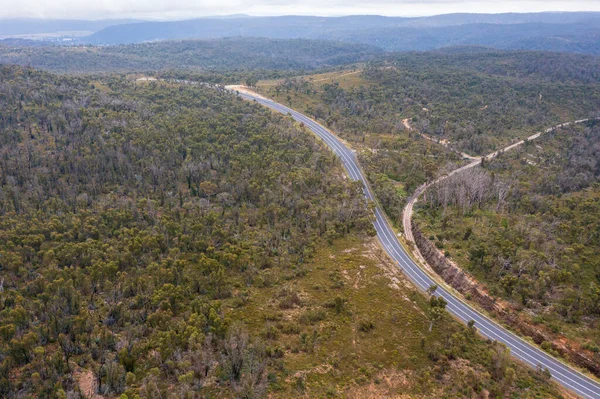 Drone aerial photograph of a highway running through a large forest in The Central Tablelands of New South Wales in Australia.