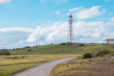 Avustralya 'nın Tazmanya Boğazı' ndaki King Island 'da bulutlu mavi bir gökyüzüne karşı Currie Deniz Feneri' ne giden toprak yolun fotoğrafı.