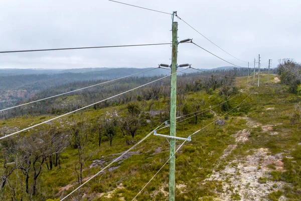 stock image Drone aerial photograph of a green wooden powerline pole with a multitude of transmission wires and connectors