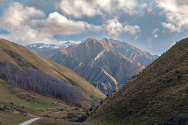 Yeni Zelanda 'nın güney adası Queenstown yakınlarındaki Moke Lake Reserve' de dolambaçlı bir yolda geniş bir sıradağların fotoğrafı.