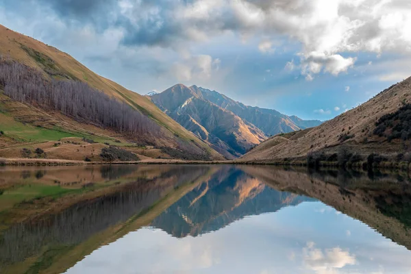 Kirkpatrick Gölü 'nün, Yeni Zelanda' nın Güney Adası 'ndaki Queenstown dışında bulutlu bir günde suya yansıyan dağlarla çekilmiş fotoğrafı.