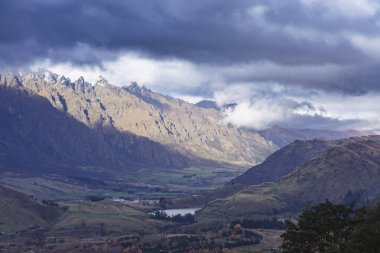 Fotoğraf: Yeni Zelanda 'nın güney adasındaki Queenstown' da bulutlu bir günde Coronet Tepesi 'nden bir sıradağ ve büyük bir tarım vadisi.