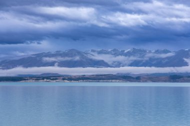 Tekapo Gölü 'nün fotoğrafı. Yeni Zelanda' nın güney adasının arka planında kar örtülü dağlar var.