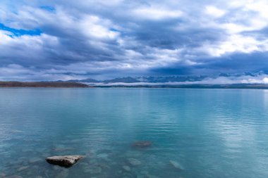 Tekapo Gölü 'nün fotoğrafı. Yeni Zelanda' nın güney adasının arka planında kar örtülü dağlar var.