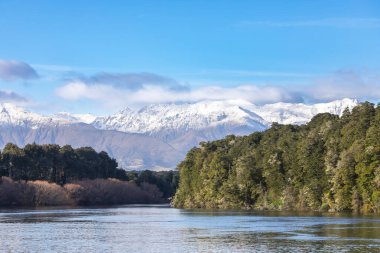 Yeni Zelanda 'nın güney adasındaki Fiordland' daki Manapouri Tekne Kulübü 'ndeki Waiau Nehri' ndeki karlı dağların ve sel sularının fotoğrafı.