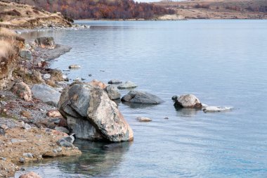 Yeni Zelanda 'nın güneyindeki Tekapo Gölü' nün kayalık kıyı şeridinin fotoğrafı.