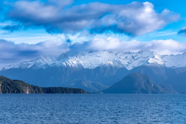 フィールドランドのテ アナウからニュージーランドの南島のマナプーリまでの運転中の大きな青い湖と雪に覆われた山脈の写真 ストック写真