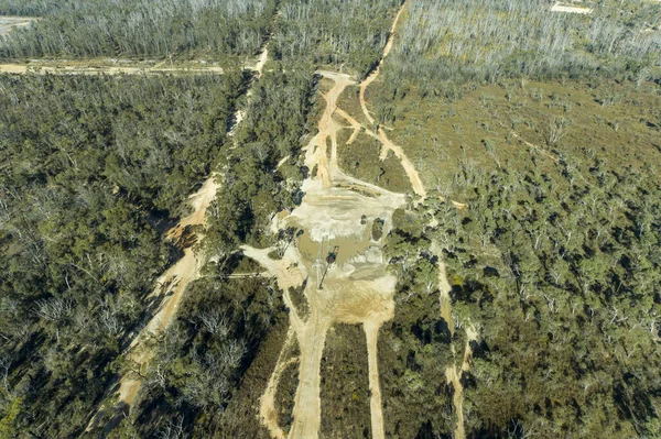 オーストラリアのニューサウスウェールズ州中央タブランドのブッシュファイアの影響を受けた大きな森を走る無人機の電話回線と汚れたトラックの航空写真 — ストック写真