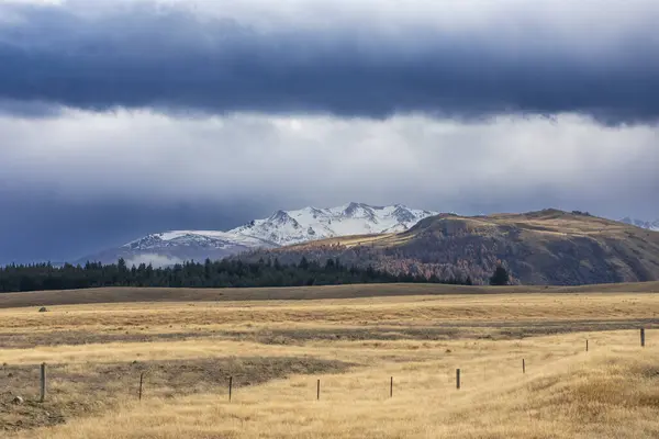 Fotografie Zasněženého Pohoří Běžícího Velkým Hnědým Zemědělským Polem Nízkými Šedými — Stock fotografie