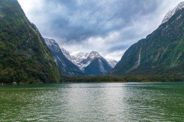 Yeni Zelanda 'nın Güney Adası' ndaki Fiordland Ulusal Parkı 'ndaki Milford Sound' da bulutların ve sisin içindeki dağların fotoğrafı.