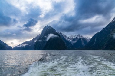 Yeni Zelanda 'nın Güney Adası' ndaki Fiordland Ulusal Parkı 'ndaki Milford Sound' da bulutların ve sisin içindeki dağların fotoğrafı.