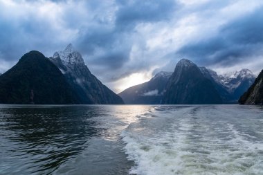 Yeni Zelanda 'nın Güney Adası' ndaki Fiordland Ulusal Parkı 'ndaki Milford Sound' da bulutların ve sisin içindeki dağların fotoğrafı.