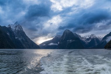 Yeni Zelanda 'nın Güney Adası' ndaki Fiordland Ulusal Parkı 'ndaki Milford Sound' da bulutların ve sisin içindeki dağların fotoğrafı.