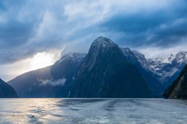 Yeni Zelanda 'nın Güney Adası' ndaki Fiordland Ulusal Parkı 'ndaki Milford Sound' da bulutların ve sisin içindeki dağların fotoğrafı.