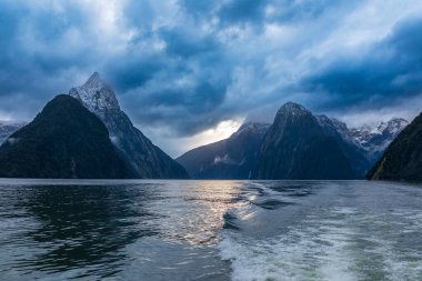 Yeni Zelanda 'nın Güney Adası' ndaki Fiordland Ulusal Parkı 'ndaki Milford Sound' da bulutların ve sisin içindeki dağların fotoğrafı.