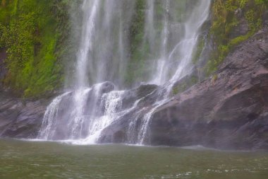 Şiddetli yağmurdan ve soğuk havadan sonra Yeni Zelanda 'nın güneyindeki Fiordland Ulusal Parkı' ndaki Milford Sound 'da Su Şelalesi' nin fotoğrafı.