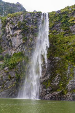 Şiddetli yağmurdan ve soğuk havadan sonra Yeni Zelanda 'nın güneyindeki Fiordland Ulusal Parkı' ndaki Milford Sound 'da Su Şelalesi' nin fotoğrafı.