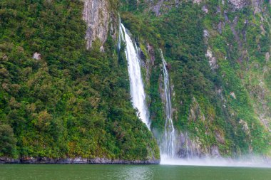 Şiddetli yağmurdan ve soğuk havadan sonra Yeni Zelanda 'nın güneyindeki Fiordland Ulusal Parkı' ndaki Milford Sound 'da Su Şelalesi' nin fotoğrafı.