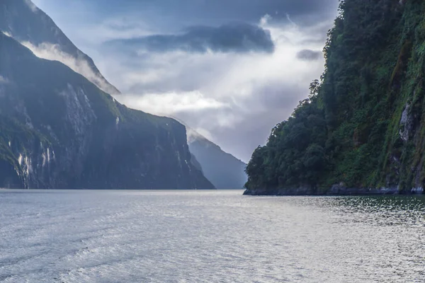 Yeni Zelanda 'nın Güney Adası' ndaki Fiordland Ulusal Parkı 'ndaki Milford Sound' da bulutların ve sisin içindeki dağların fotoğrafı.