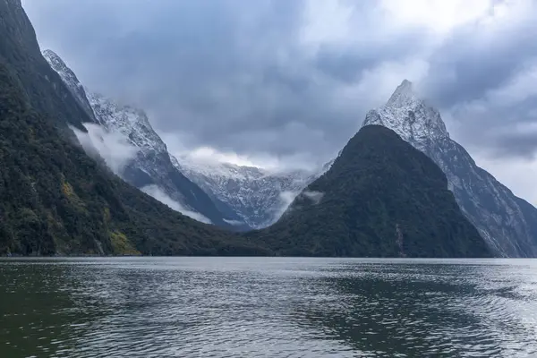 stock image Photograph of mountains in clouds and mist viewed from the water in Milford Sound in Fiordland National Park on the South Island of New Zealand