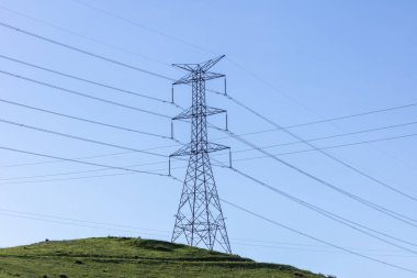 Avustralya 'nın Mavi Dağları' ndaki yeşil ve çimenli bir tepenin üzerinde bulunan büyük bir telekomünikasyon kulesinin fotoğrafı.